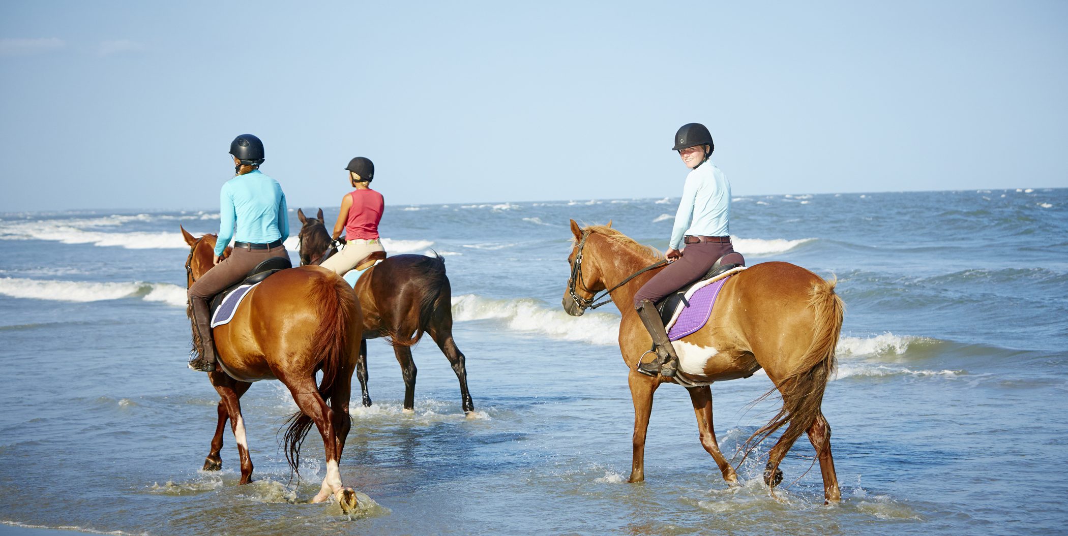 women riding horses in the ocean