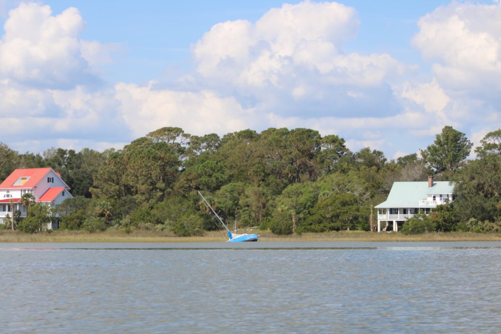 sunken blue sailboat by two houses
