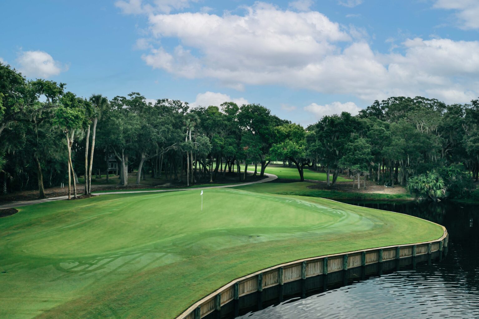Scenic golf course green surrounded by water and forest on Seabrook Island, highlighting the luxury amenities and natural beauty within the island’s gated communities.