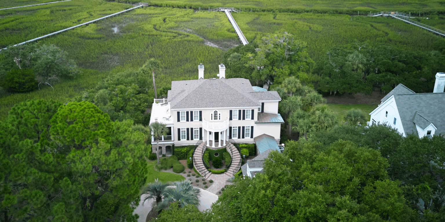 Elegant coastal home on Seabrook Island with stunning curb appeal, symmetrical brick staircase entry, manicured landscaping, and expansive marsh views with private dock access.